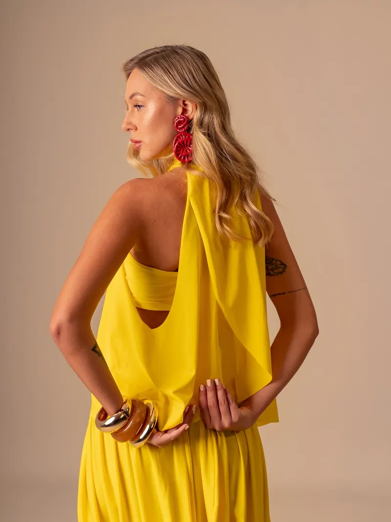 Modelo de costas com conjunto amarelo, no fundo infinito